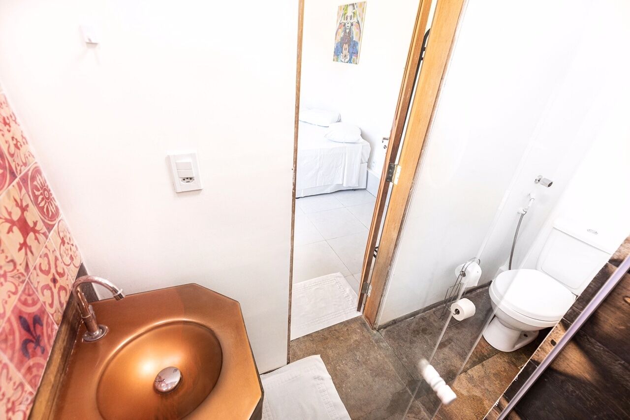 A bathroom with a copper sink, a toilet, and a shower area.