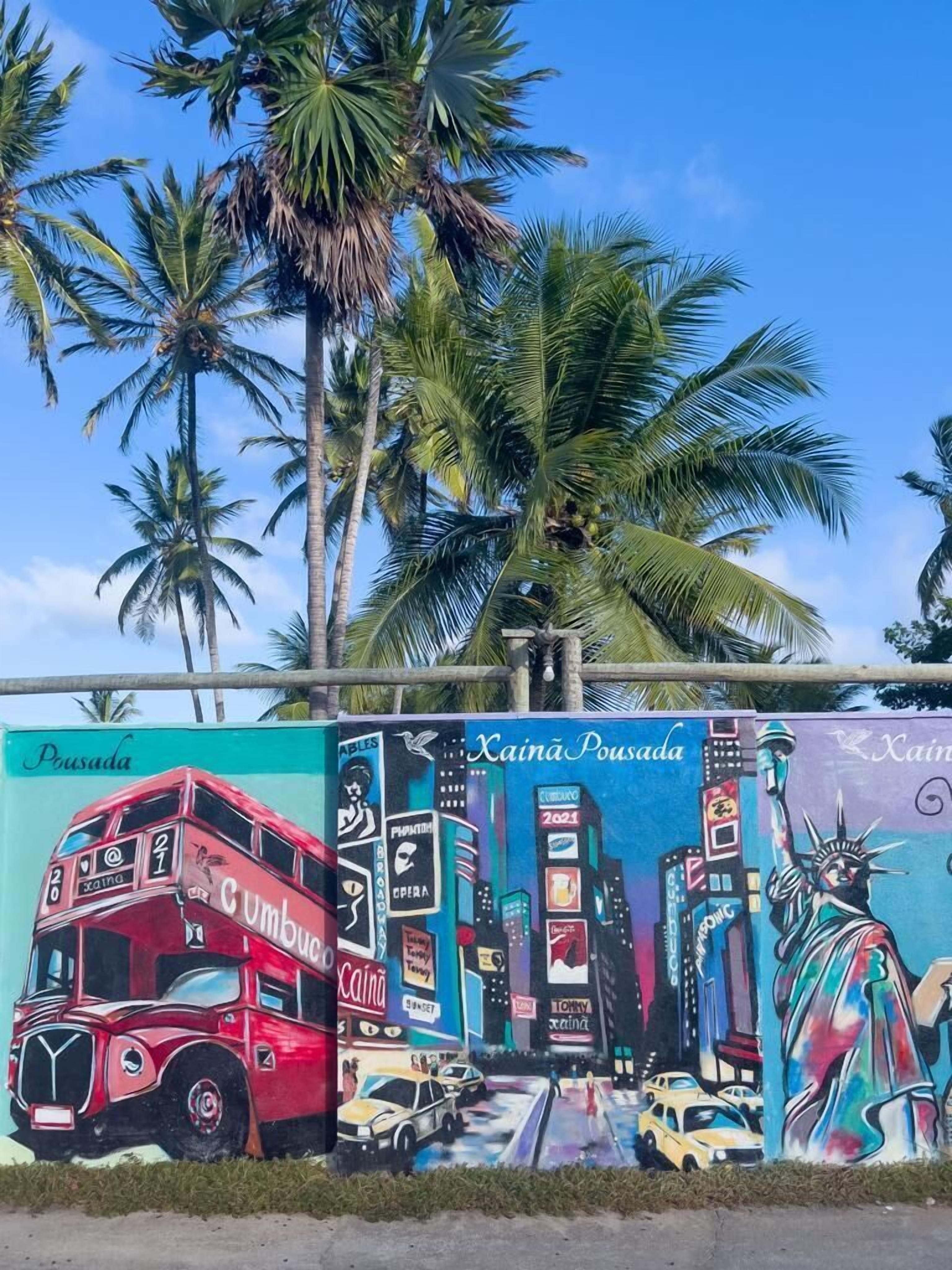 Un mural con un autobús de dos pisos, palmeras y un paisaje urbano.