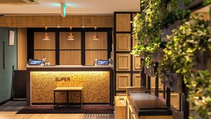 Uma receção com um letreiro 'SUPERHOTEL', painel de madeira e uma planta suspensa na parede.
