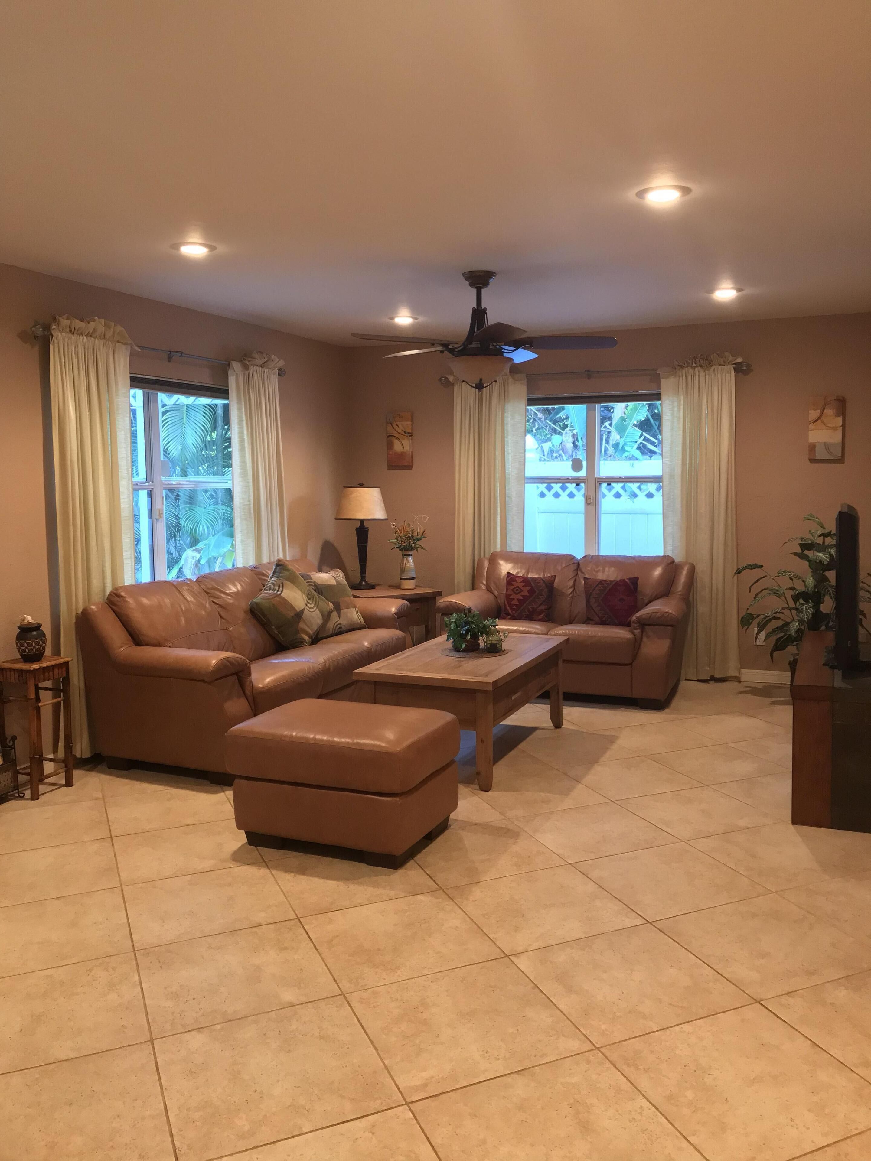 A living room with two leather sofas, a wooden coffee table, and a ceiling fan.