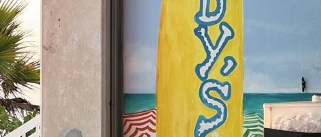A surfboard-shaped sign with the name 'CADDY'S' painted on it.