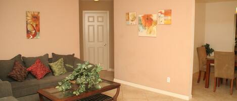 A living room with a sofa, coffee table, and artwork on the walls.