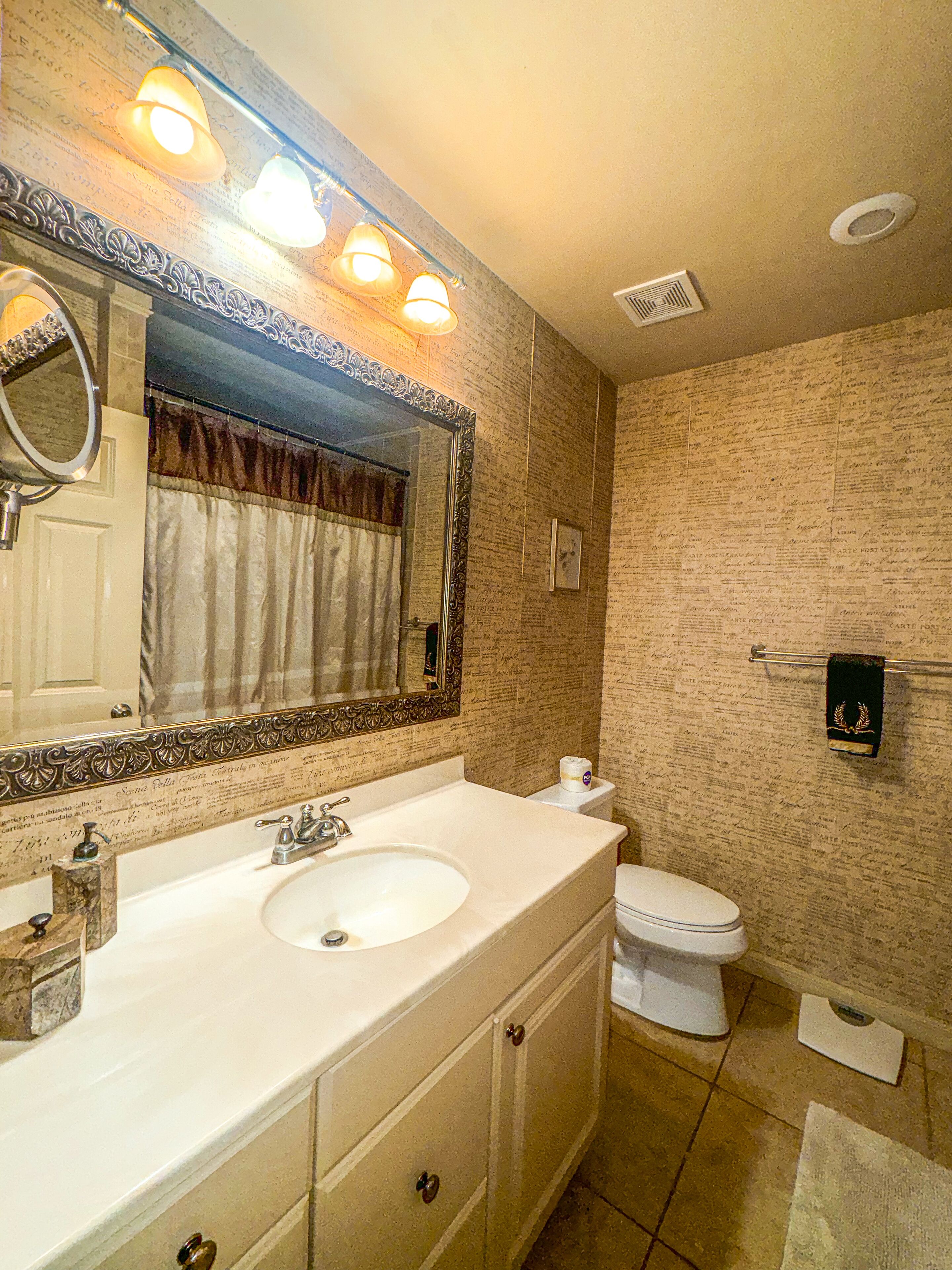 Une salle de bain avec un grand miroir, deux lavabos, des toilettes et un porte-serviettes.