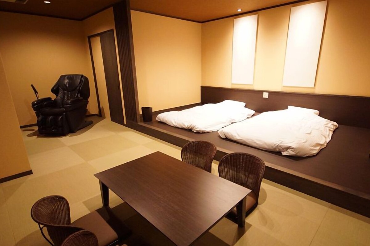 A hotel room with a bed, a chair, a table, and a small sofa.