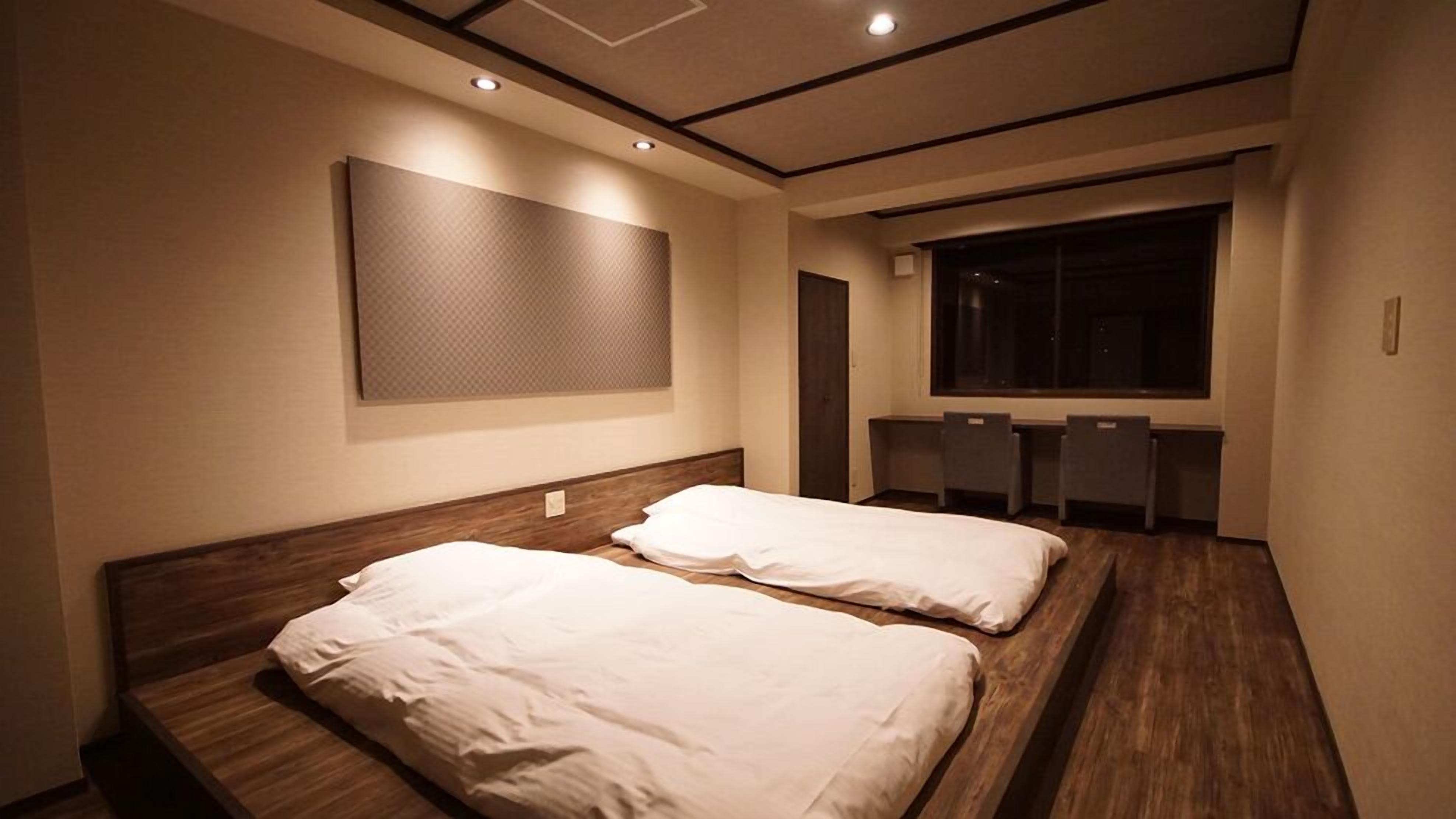 A hotel room with two beds, a large window, and a desk area.