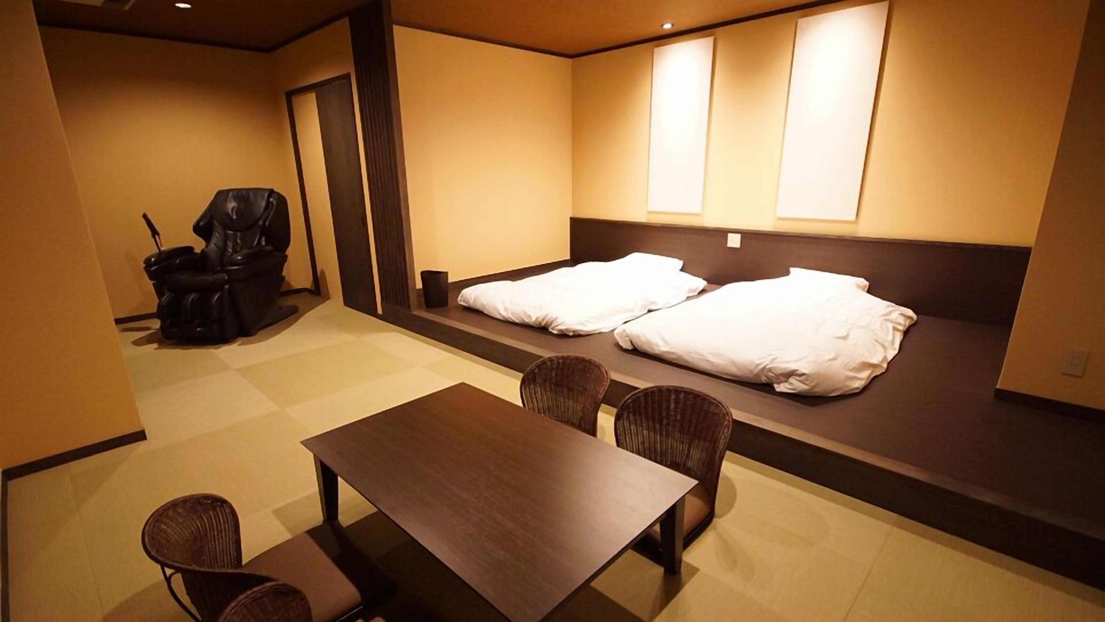 A hotel room with a bed, a chair, a table, and a small sofa.