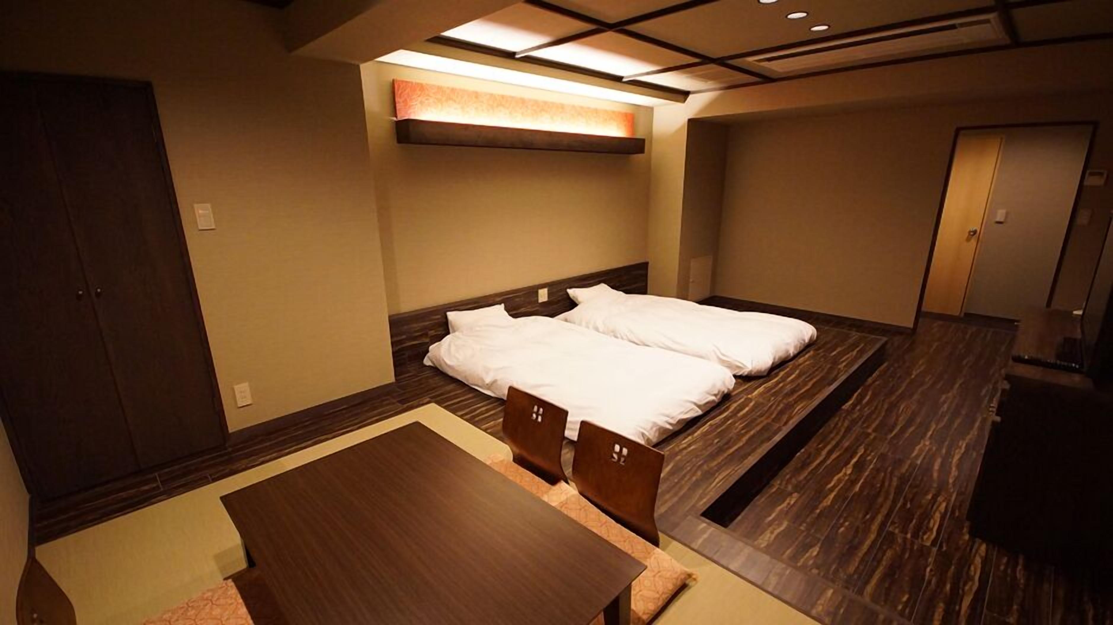 A hotel room with a bed, a desk, and a wardrobe.