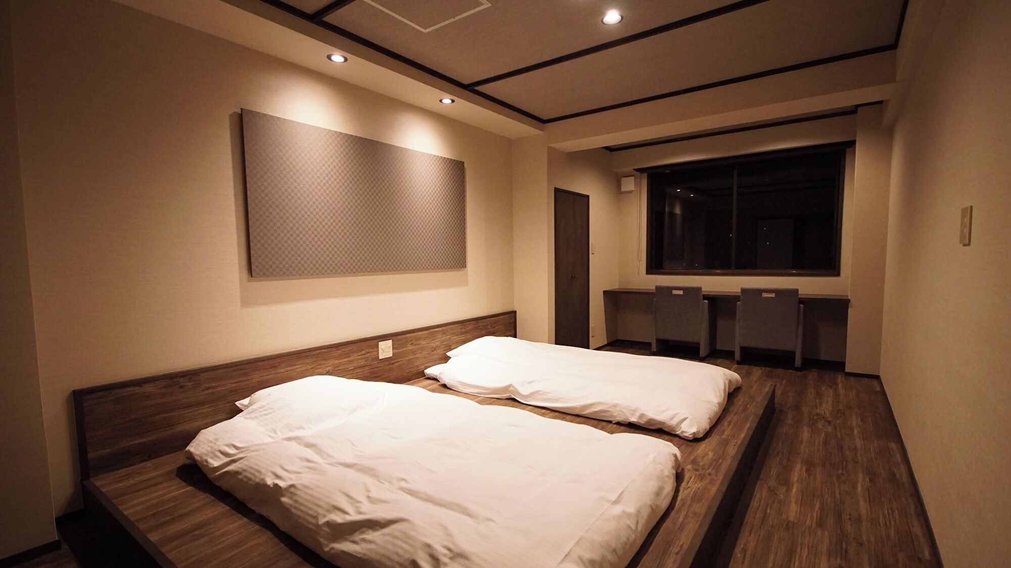A hotel room with two beds, a large window, and a wall-mounted TV.