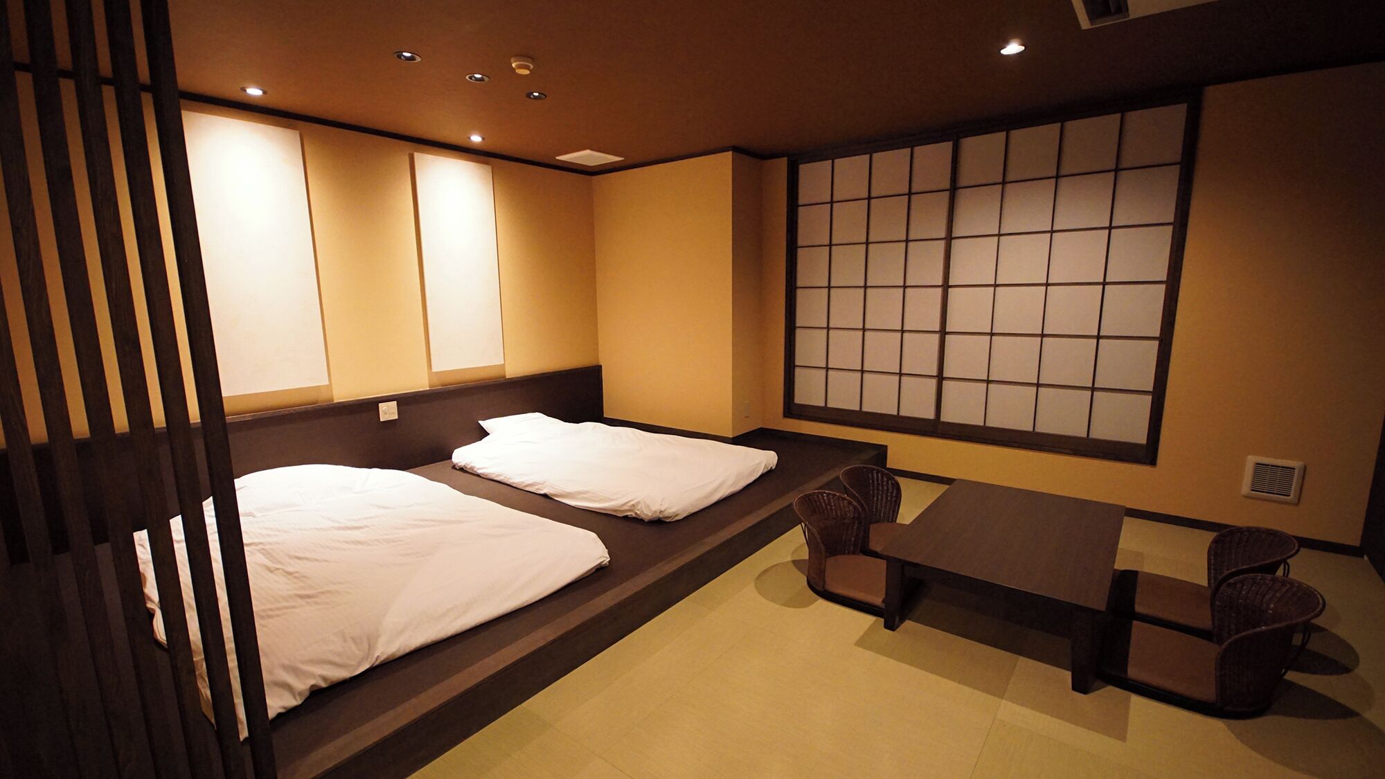 A room with two beds, a table, chairs, and a shoji screen.