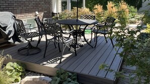 Eine Terrassengruppe mit Tisch und Stühlen, eine überdachte Sitzgelegenheit und ein Grill.