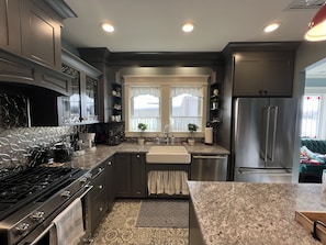 A modern kitchen with dark cabinetry, a stainless steel refrigerator, and a patterned backsplash. - Luxury Accomodations in updated 1920's bungalow in Downtown Provo (Provo)