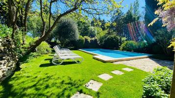 Alberca al aire libre, sombrillas en la alberca y camastros