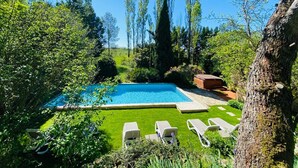 A rectangular swimming pool with a clear blue water surface, surrounded by a well-maintained lawn and several lounge chairs. - Le Clos Pastel (Virac)