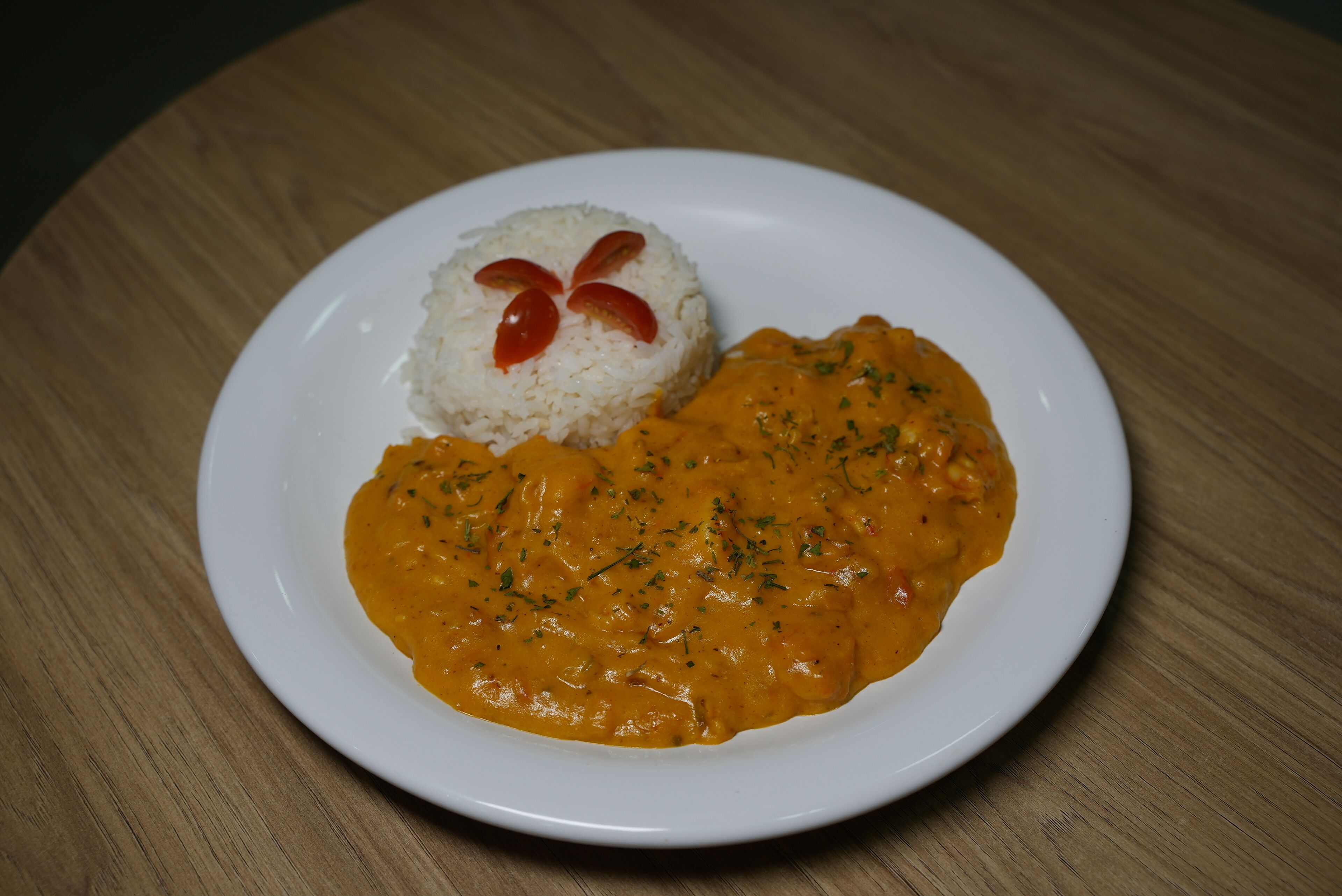 A plate with rice and curry on a wooden table.