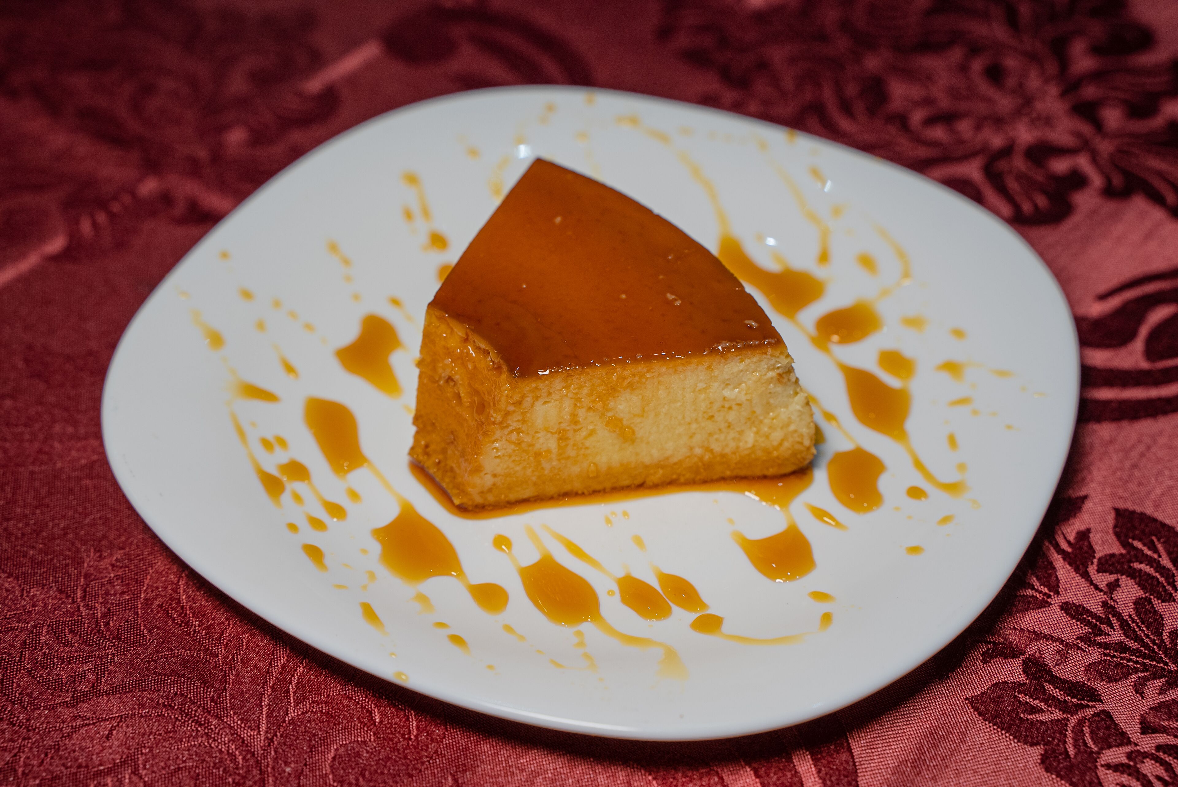 Een stukje crème brûlée op een bord met karamelsaus.