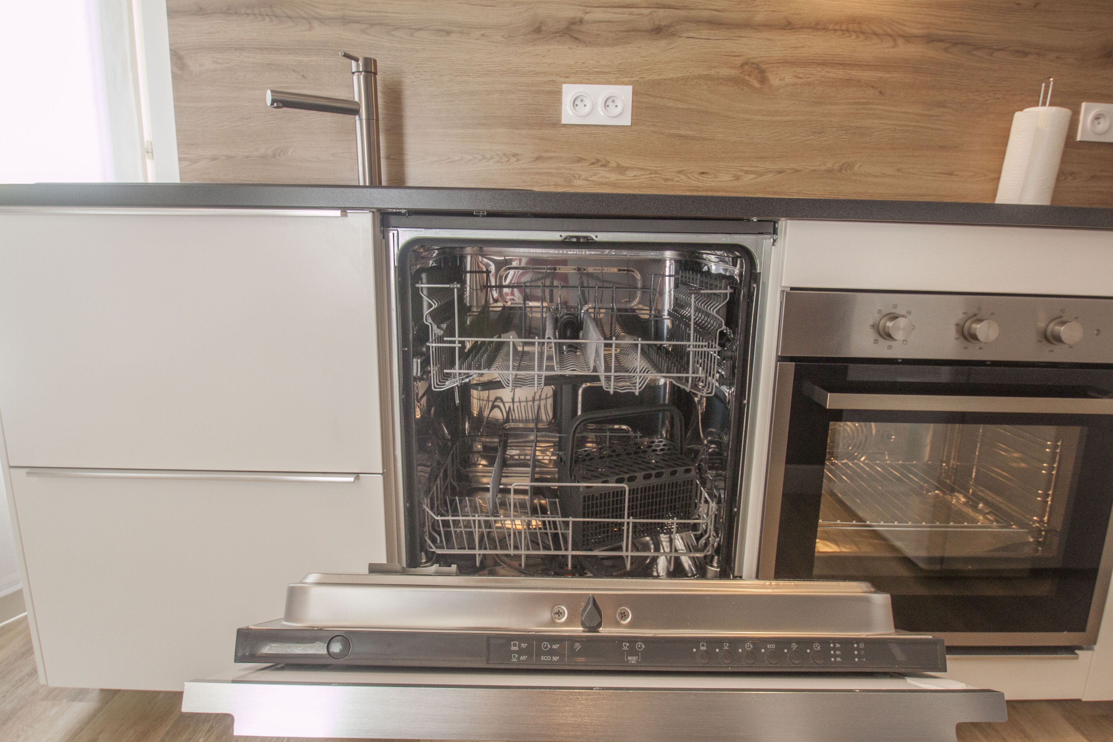 A kitchen with a dishwasher, oven, and a wooden countertop.