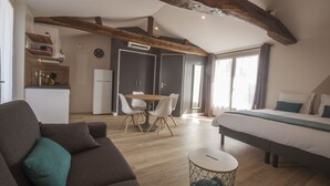 Una habitación moderna y bien iluminada con una cama grande, una mesa de comedor con sillas, un sofá y una mesita redonda.