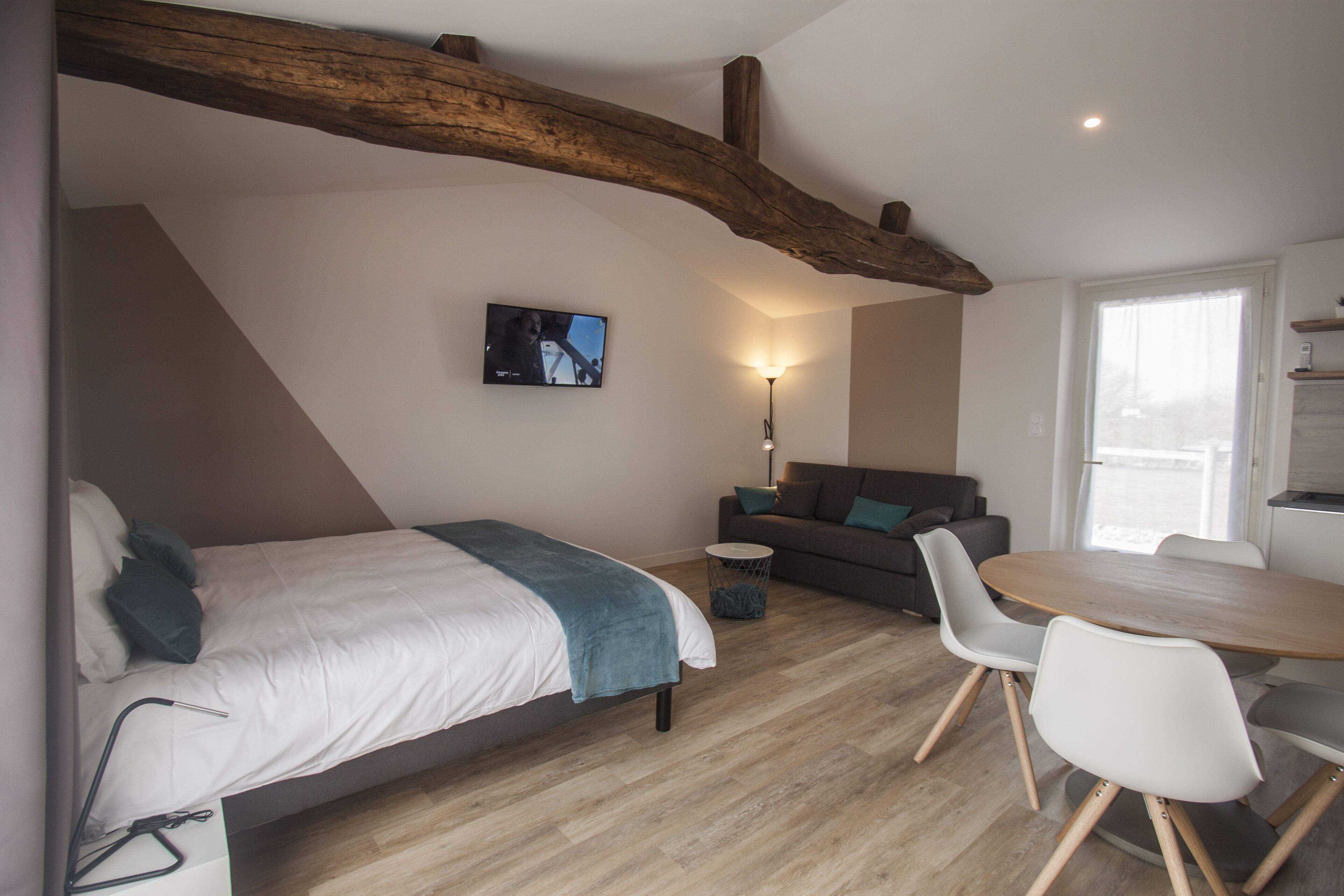 Un dormitorio moderno con cama, televisor, sofá y una mesa de comedor con sillas.