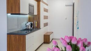 A modern kitchen with wooden cabinets, a built-in microwave, and a coffee maker. - Apart Harmony (Wladyslawowo)