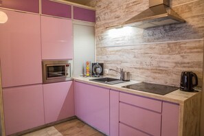 A kitchen with pink cabinets, a microwave, a kettle, and a sink. - Apart Harmony (Wladyslawowo)
