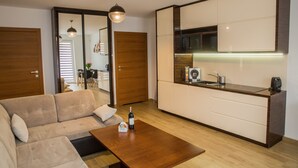 A modern living room with a sofa, a wooden coffee table, and a kitchen area with a microwave and cabinets. - Apart Harmony (Wladyslawowo)