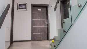 A modern staircase with glass railings and a dark door at the top. - Apart Harmony (Wladyslawowo)