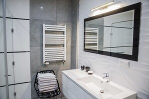 A modern bathroom with a white sink, a large mirror, and a towel rack with folded towels. - Apart Harmony (Wladyslawowo)