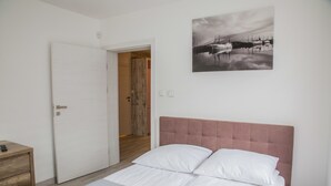 A bedroom with a bed, a bedside table, a door, and a painting on the wall. - Apart Harmony (Wladyslawowo)