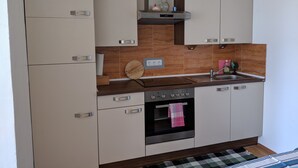 Cocina moderna con armarios blancos, encimera de madera, horno de acero inoxidable y un lavaplatos integrado.