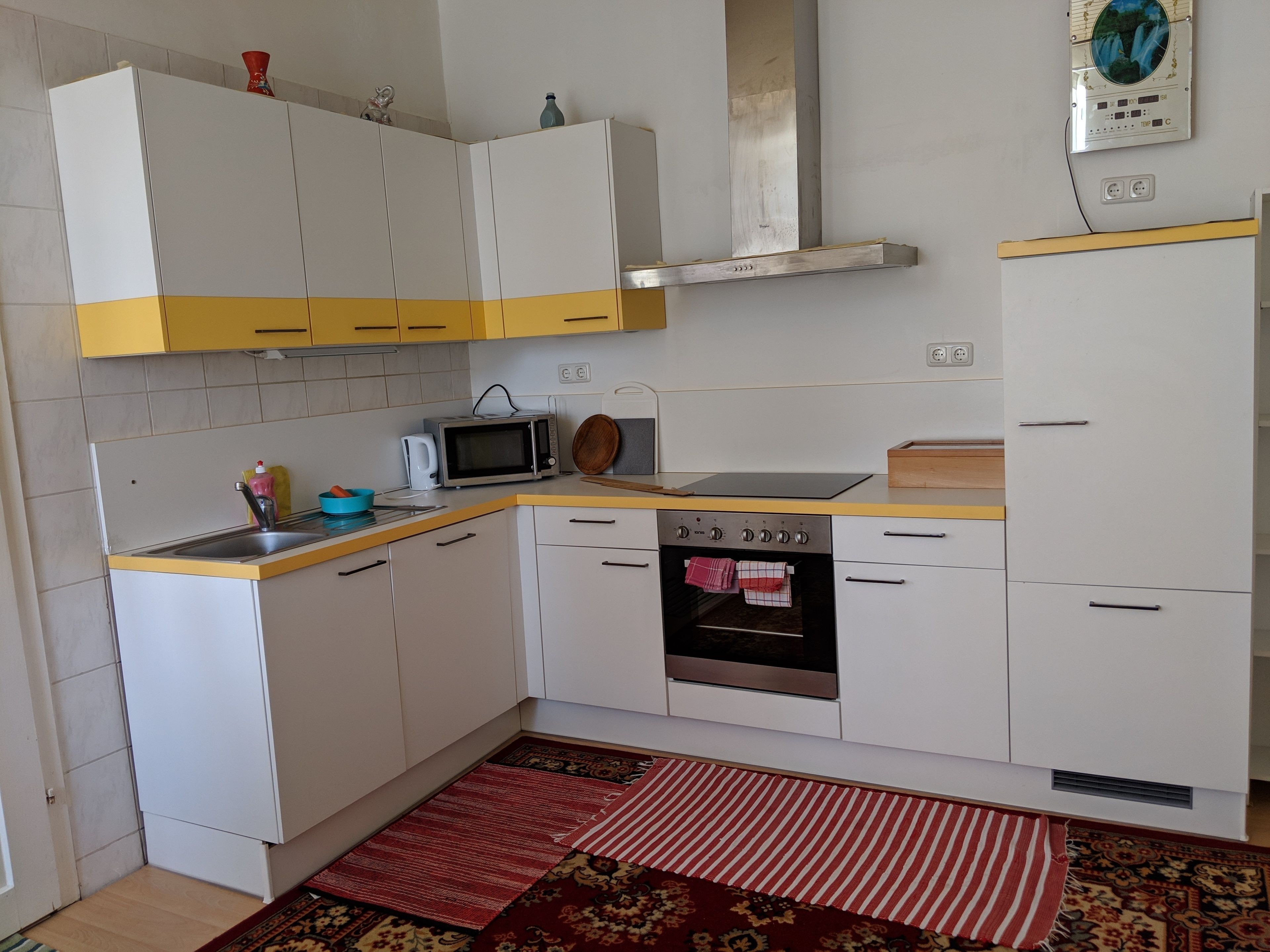 A compact kitchen with white cabinets, a microwave, an oven, and a sink.