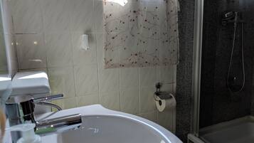 Un baño con lavamanos blanco, ducha e inodoro.