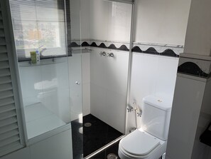 Kylpyhuone, jossa on lasiseinällä varustettu suihku, wc ja pesuallas.