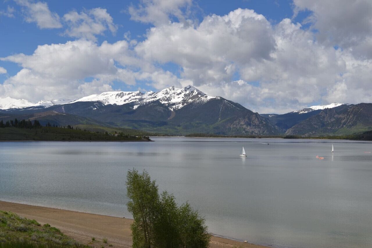 Un lac avec des montagnes en arrière-plan et un ciel dégagé.