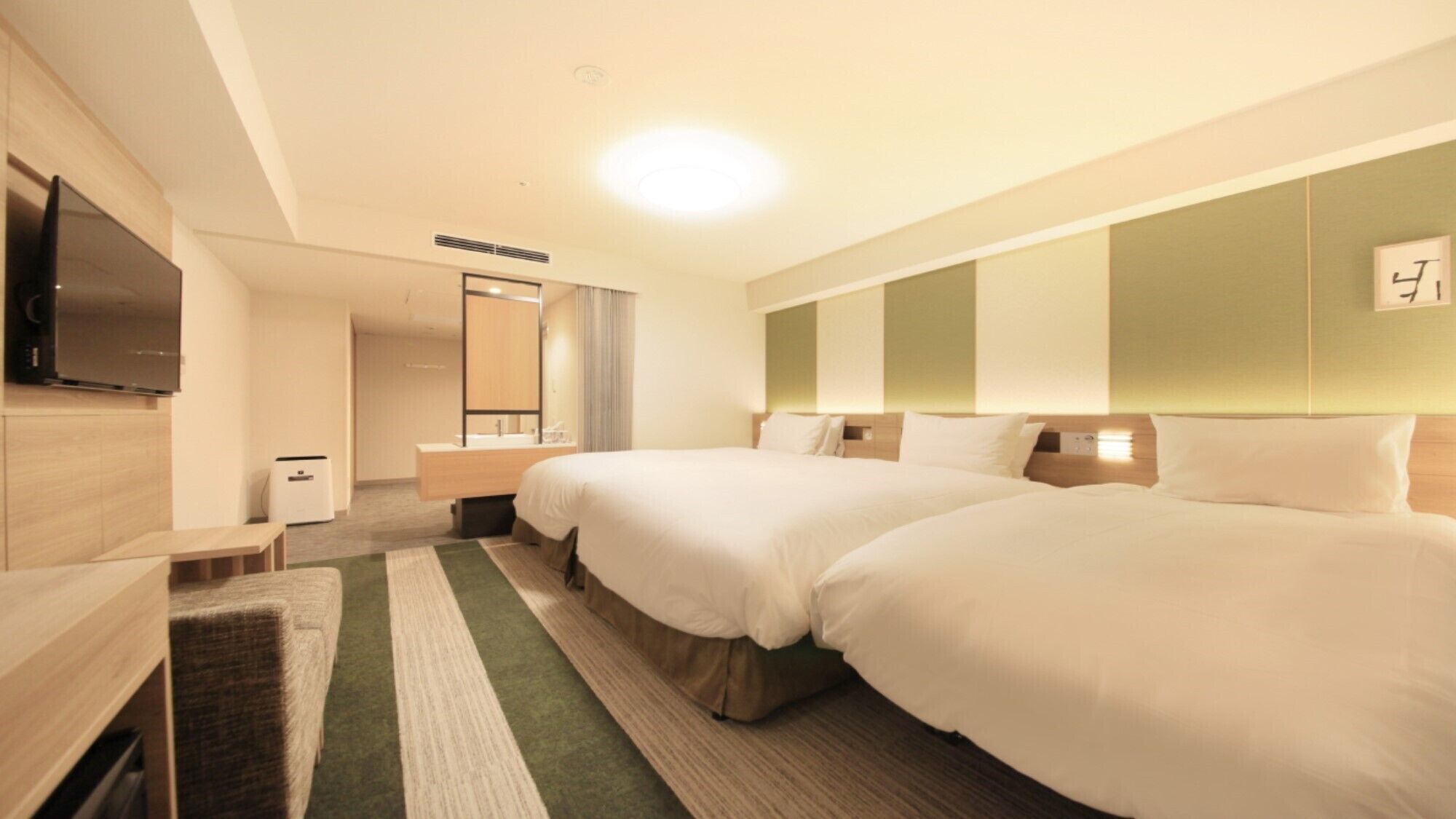 A hotel room with two beds, a TV, a desk, and a mirror.