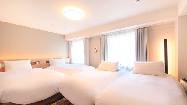 A hotel room with three beds arranged in a row, a large window with curtains, and a wall-mounted clock. - Richmond Hotel Tenjin Nishidori (Fukuoka)