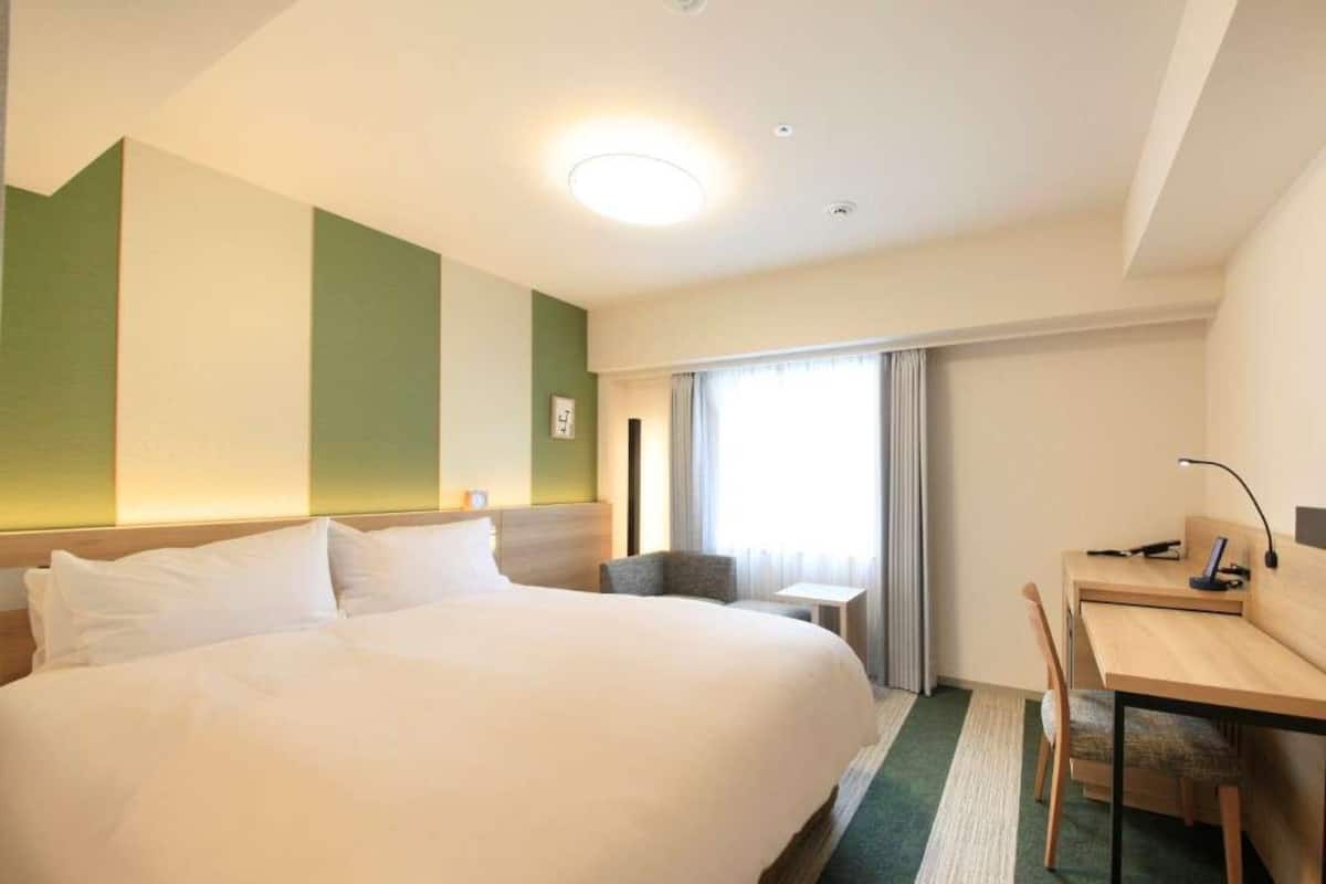 Una camera d'albergo con un letto grande, una scrivania e una sedia.