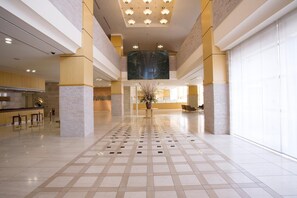 A spacious lobby with a high ceiling, a central floral arrangement, and a check-in counter to the left. - Hotel Lake View Mito (Mito)