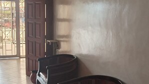 Un pasillo con dos sillas de madera, un televisor montado en la pared y una puerta que da al exterior.