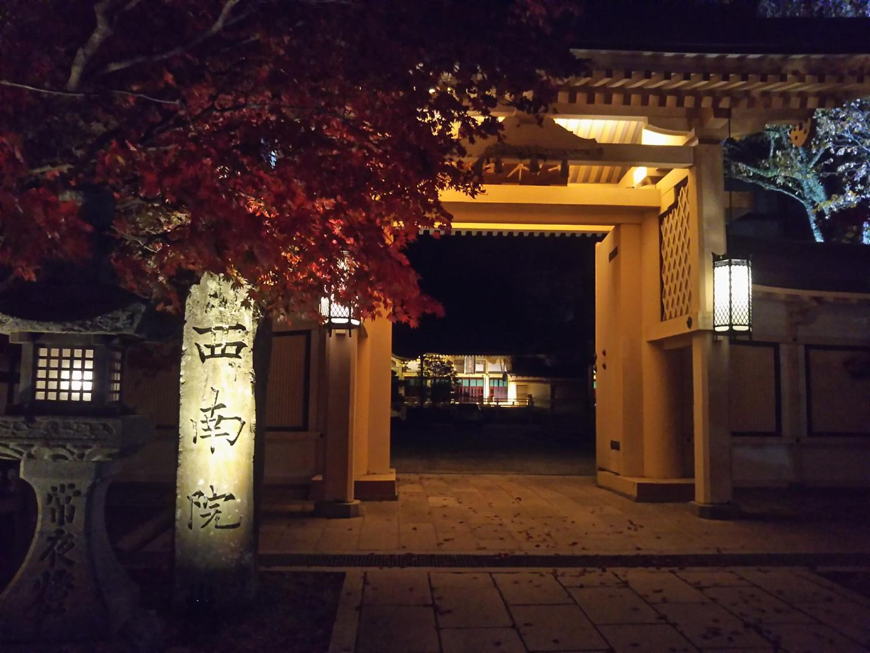 Ein traditionelles japanisches Tor mit beleuchteten Säulen und einem Laternenleuchter.