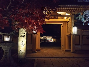 A traditional Japanese gate with illuminated pillars and a lantern. - Koyasan Sainan-In (Koya)