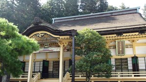 A traditional Japanese building with a curved roof, a wooden staircase, and a small bench in front. - Koyasan Sainan-In (Koya)