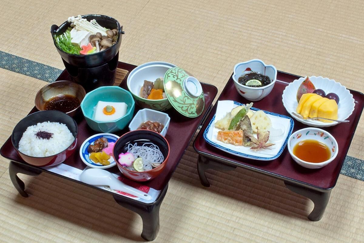 A traditional Japanese meal set on a tray with various dishes including rice, vegetables, and fish.