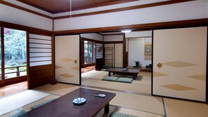 A traditional Japanese room with tatami flooring, sliding doors, and a low wooden table with cushions. - Koyasan Sainan-In (Koya)