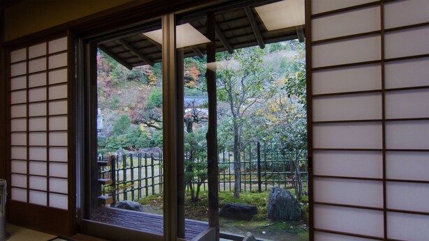 A traditional Japanese room with tatami flooring, a shoji screen, and a view of a garden with rocks and trees. - Koyasan Sainan-In (Koya)