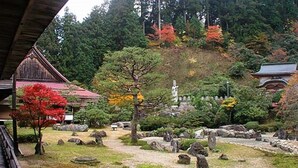 A traditional Japanese garden with a wooden structure, stone lanterns, and a variety of trees. - Koyasan Sainan-In (Koya)
