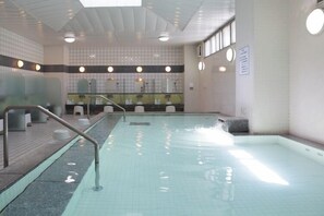 An indoor swimming pool with a tiled floor, a metal handrail, and a bench. - Hotel Blanca (Arao)
