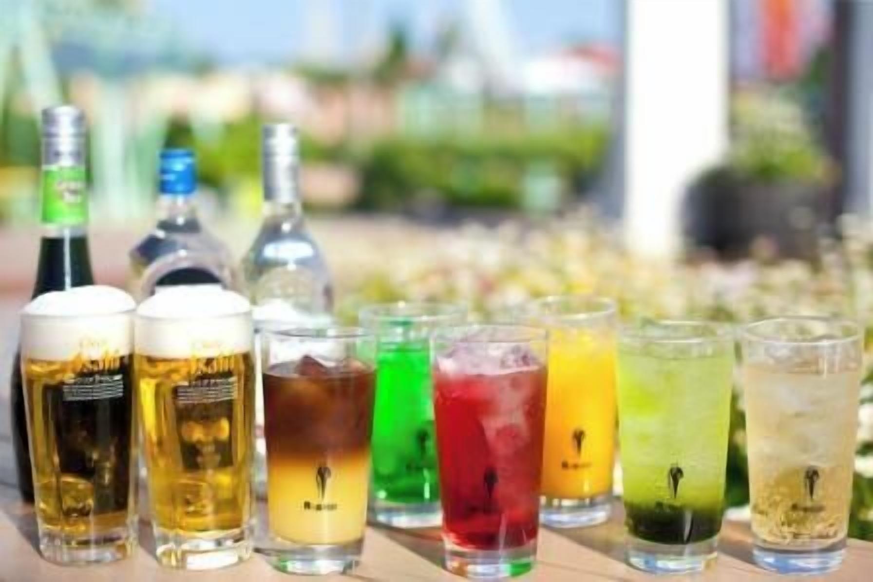 A variety of beverages, including beer and cocktails, displayed on a table outdoors.