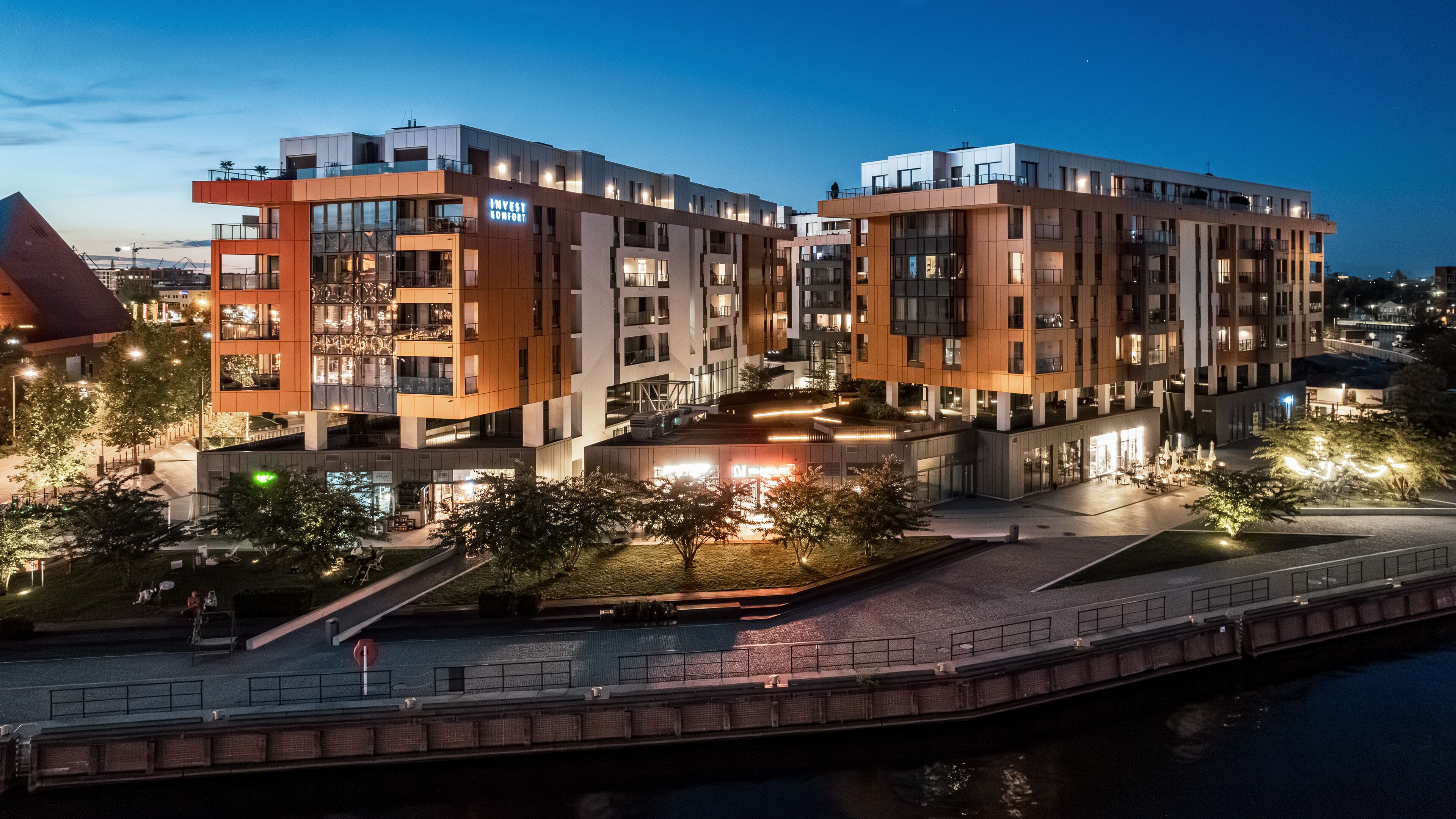 Ein modernes, mehrstöckiges Gebäude mit flachem Dach, großen Fenstern und einer gut beleuchteten Fassade.