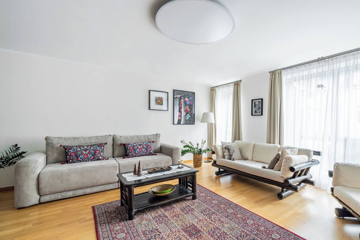 A modern living room with a sofa, armchairs, a coffee table, and a rug.