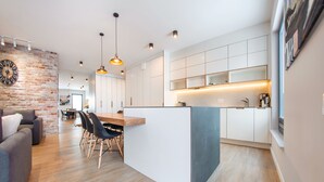 Une cuisine moderne avec des meubles blancs, un îlot central en bois et des luminaires suspendus.